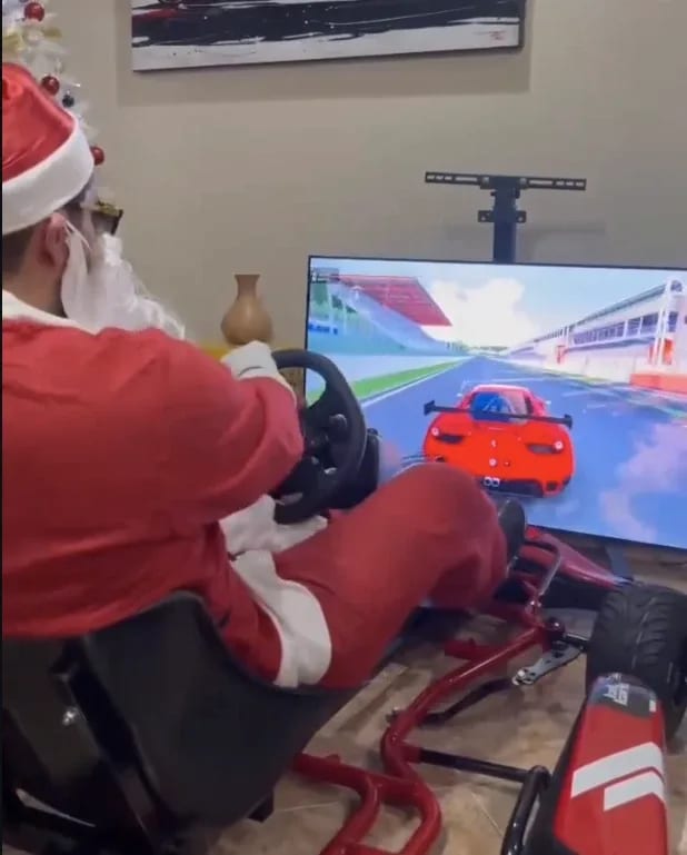 A man dressed as Santa Claus driving the kart simulator at home